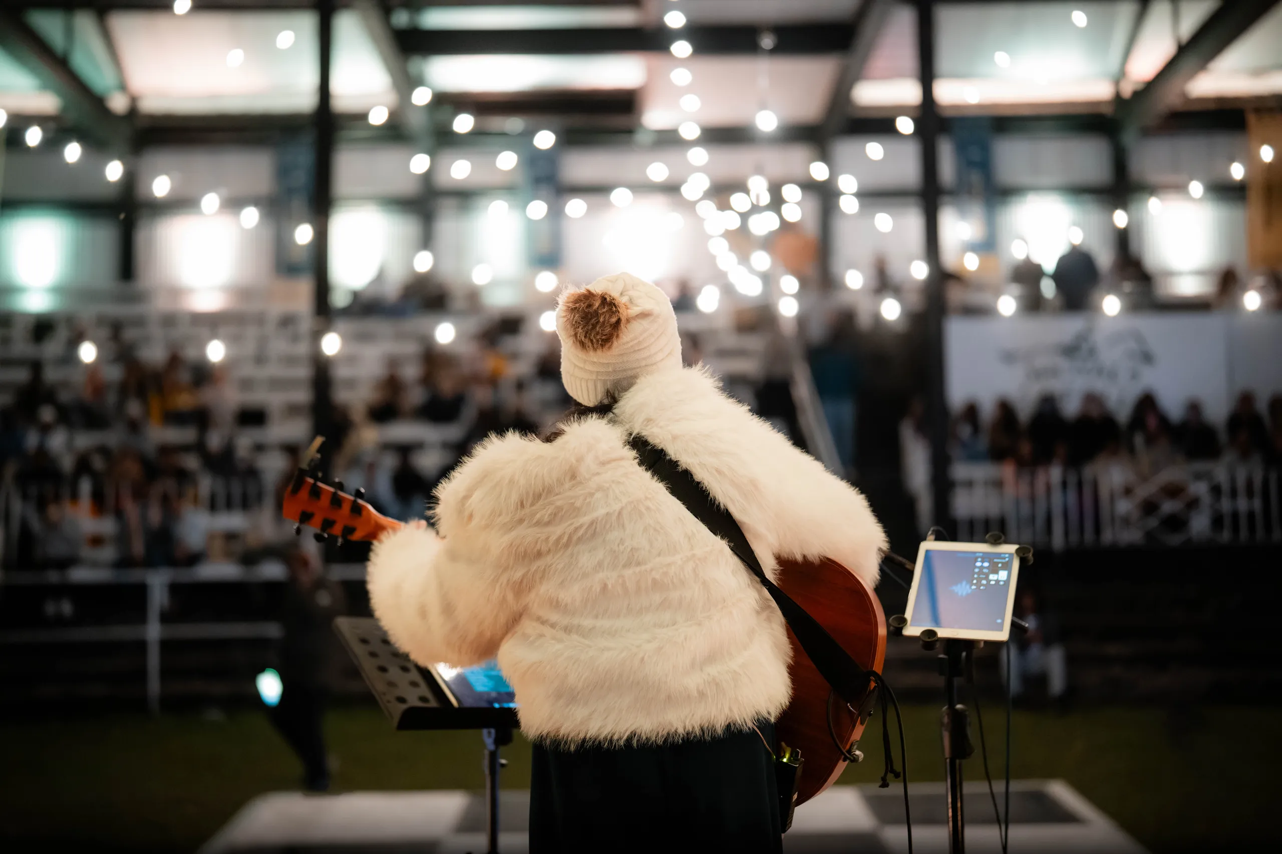 A guitarist facing the audience through a canopy of bulbs